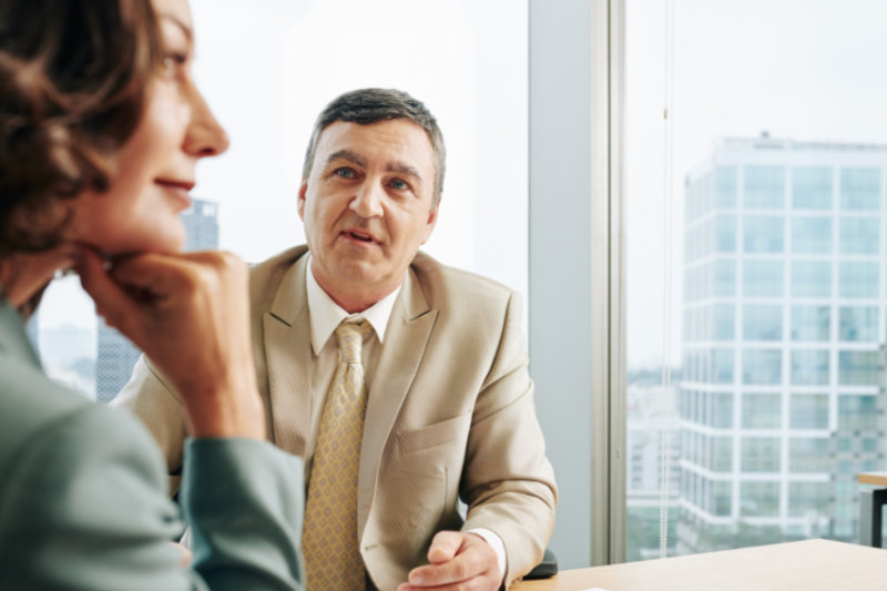 Mature Caucasian businessman and businesswoman working together at office desk, horizontal shot