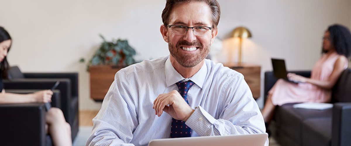 businessman-using-laptop-at-desk-smiling-to-camera-2024-10-19-06-48-29-utc_res